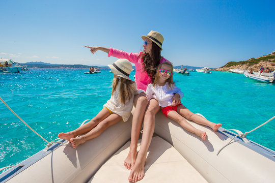 Young mother with her adorable baby girls resting on a big boat