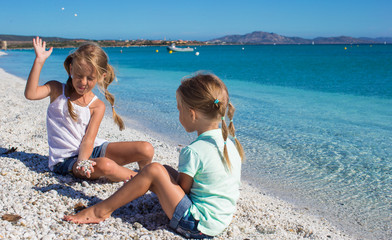 Fototapeta na wymiar Adorable cute girls have fun on white beach during vacation