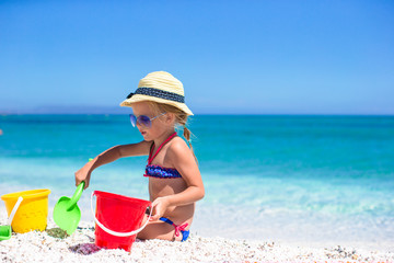 Adorable little girl playing with toys on beach vacation