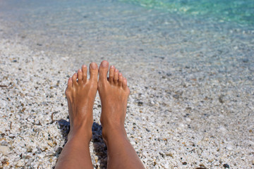 Female legs walking at the tropical beach on the sand