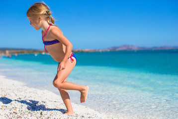 Fototapeta na wymiar Adorable little girl in shallow water have fun at white beach