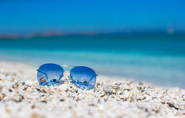 Fototapeta na wymiar Close up of colorful blue sunglasses on tropical beach.