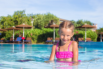 Naklejka premium Cute happy little girl in the swimming pool looking at camera