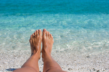 Closeup of female legs background of the turquoise sea
