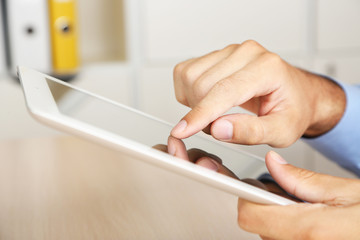 Man working on tablet on wooden background closeup