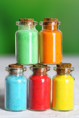 Bottles with colorful dry pigments on bright background