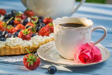 Close-up on coffee and tart with strawberries and blueberries