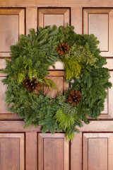 Fototapeta na wymiar Green Evergreen Christmas Wreath On Wooden Door