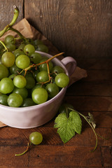 Green grapes in bowl on wooden background