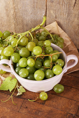 Green grapes in bowl on wooden background
