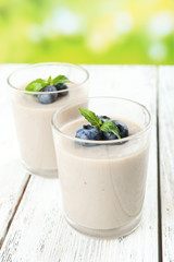 Delicious berry mousse in glasses on table on bright background