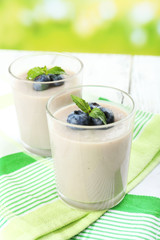 Delicious berry mousse in glasses on table on bright background