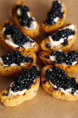 Slices of bread with butter and black caviar on paper