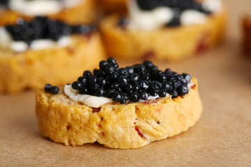 Slices of bread with butter and black caviar on paper