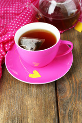 Cup of tea, teapot and tea bags on wooden table close-up