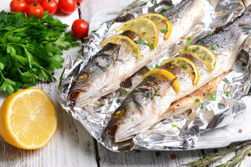 Tasty baked fish in foil on table close-up