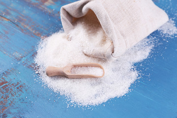 Sugar in bag on color wooden background