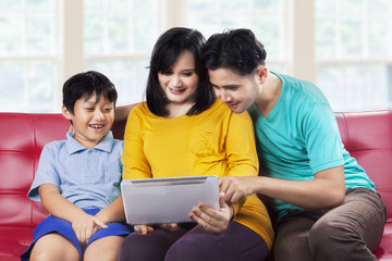 Obraz premium Happy family using digital tablet on couch