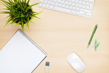 Office table with notepad, computer and flower