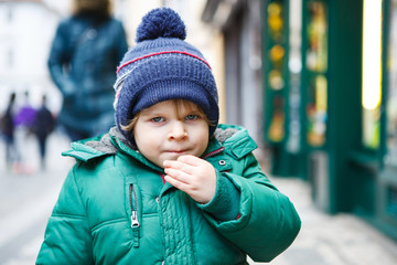 Portrait of little toddler boy walking through the city on cold