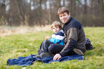 Naklejka na ściany i meble Young father and little son having picnic and fun near forest la
