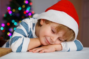 Little boy in santa hat with christmas tree and lights