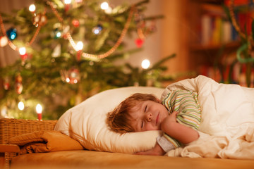 Obraz na płótnie Canvas Little cute blond boy sleeping under Christmas tree