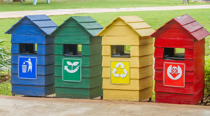 Blue, green, yellow and red bins on stand near footpath.