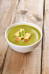 Spinach soup with dried crusts on wooden table