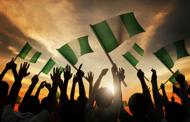 Silhouettes of People Holding Flag of Nigeria - obrazy, fototapety, plakaty