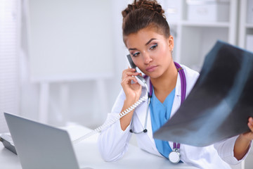 Female doctor looking x-ray scan and talking on phone in