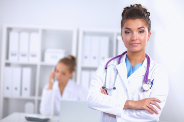 Portrait of young woman doctor with white coat standing in