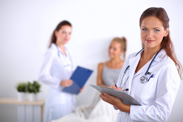 Fototapeta premium Smiling female doctor with a folder in uniform standing at
