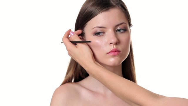 Beautiful woman applying make up on white background