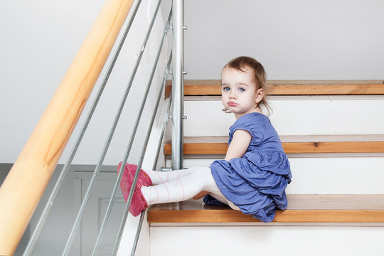Little girl sitting on steps sad