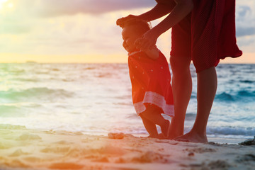 Fototapeta na wymiar mother and little daughter walking on sand beach