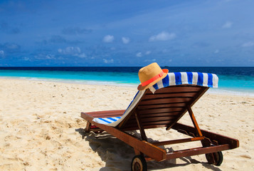 Fototapeta na wymiar straw hat on a lounge chair at sand beach