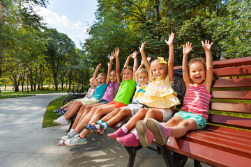 Group of kids on the bench cheering lifting hands