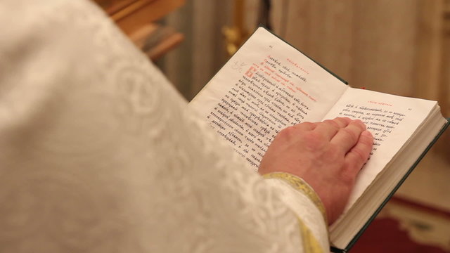 hands of praying priest on the Bible 1080p