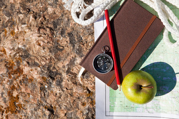 Notebook, compass, apple, rope on stone background