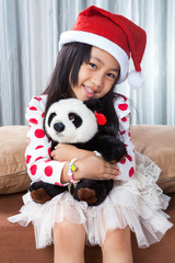 smiling girl in santa helper hat with teddy bear
