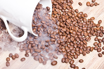 Fallen white coffee mug with coffee beans all around.