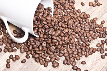 Fallen white coffee mug with coffee beans all around.