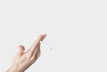 male hand holding a cigarette isolated on grey