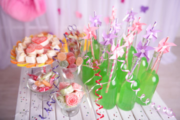 Bottles of drink with straw and sweets on decorative background