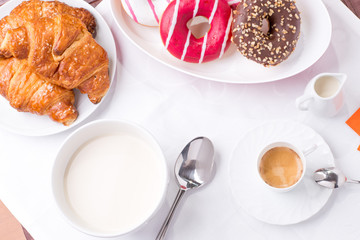 Prima colazione con donuts, brioches, latte e caffè