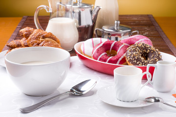 Prima colazione con donuts, brioches, latte e caffè