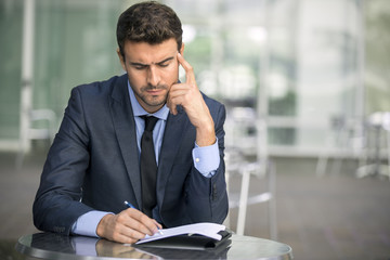 Focused businessman thinking and writing outside office
