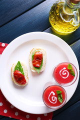 Gazpacho soup in glasses, on color wooden background