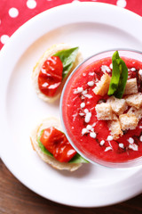 Gazpacho soup in glass bowl, on color wooden background